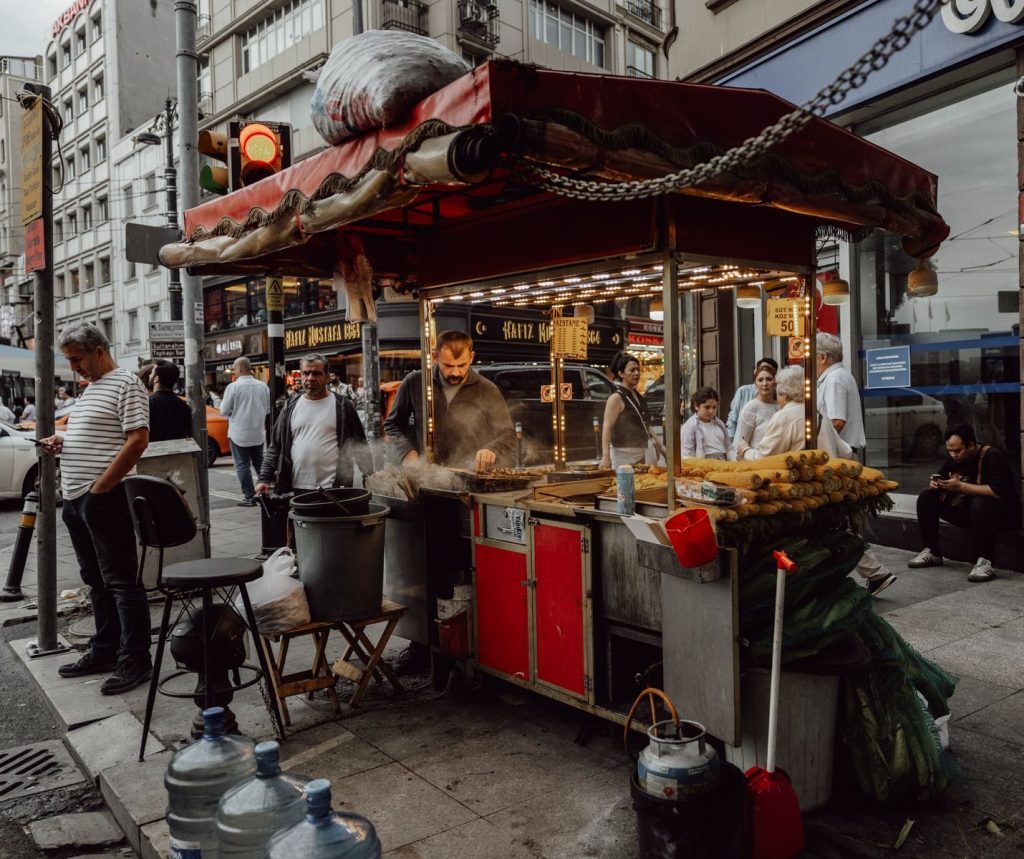 istanbul street vendor prepares grilled corn and chestnuts on a busy urban street, attracting passersby.
