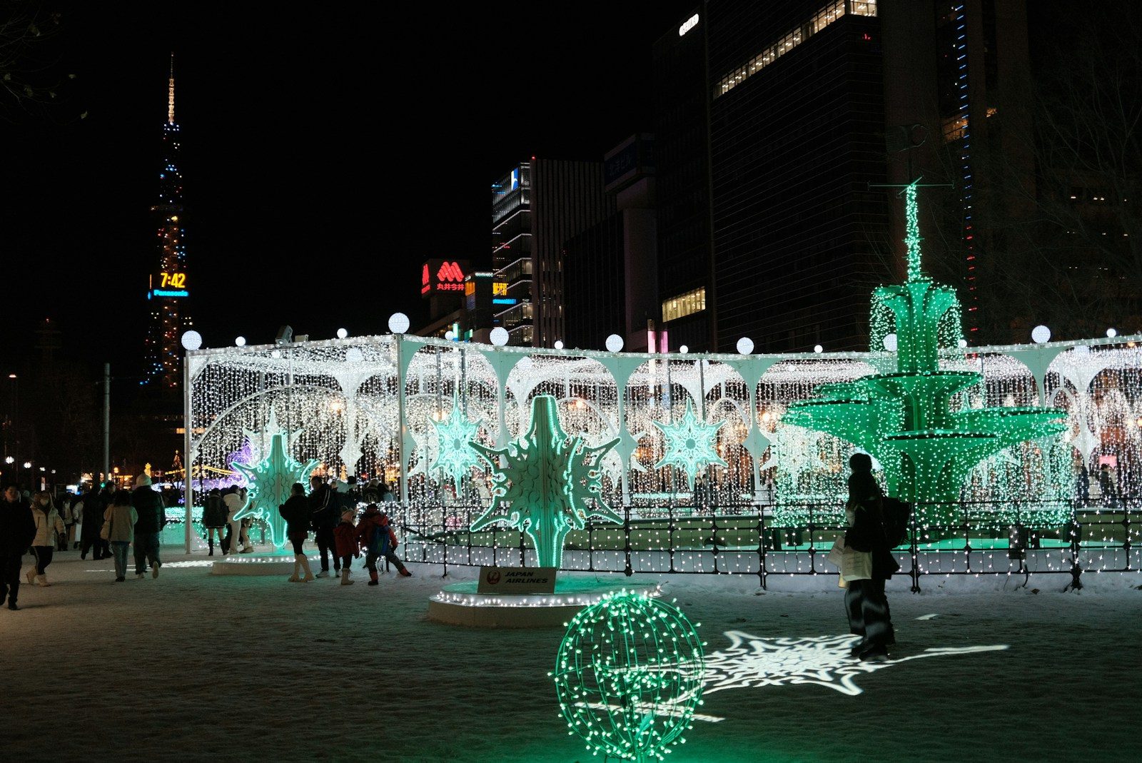 A group of people standing around a lit up fountain