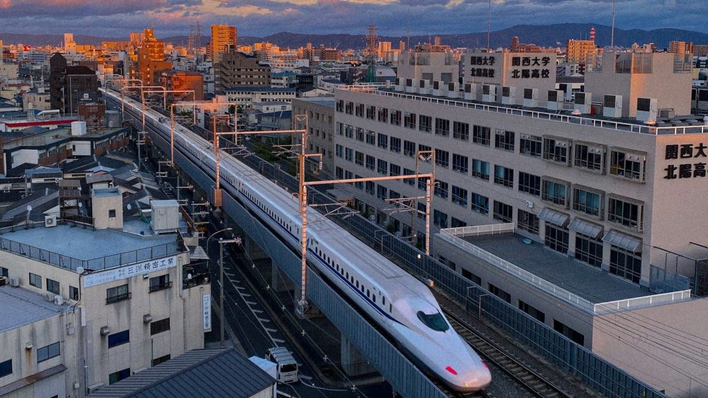 A train traveling through a city next to tall buildings